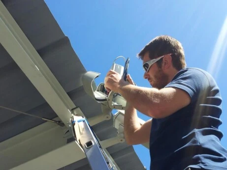 Installazione telecamera videosorveglianza esterna Tecnico installa una telecamera di videosorveglianza su una struttura esterna sotto il sole