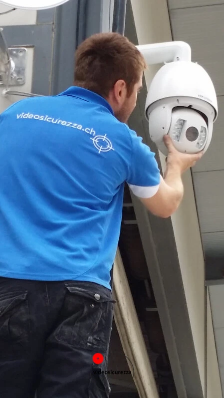 Telecamera dome di Cisco da interno installata su soffitto in legno Telecamera di videosorveglianza dome montata su soffitto in legno con parete in intonaco bianco e dispositivo di rete sullo sfondo