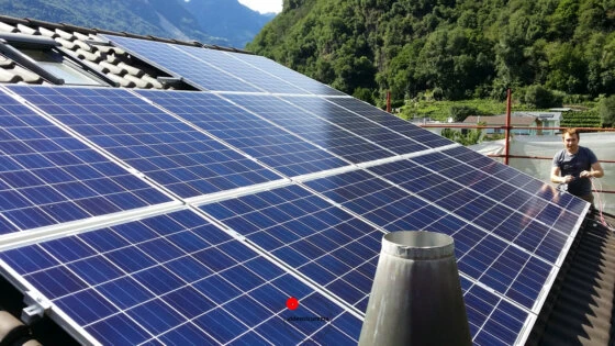 Installazione impianto fotovoltaico su tetto inclinato in zona montana Pannelli solari installati su tetto in tegole con sfondo montano e tecnico al lavoro