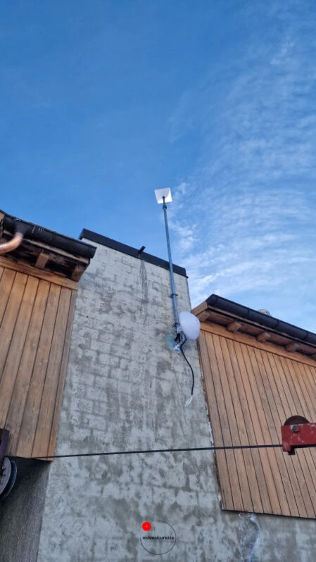 Installazione antenna Starlink su casa in legno e muratura Antenna Starlink montata su parete esterna di abitazione con rivestimento in legno e muro in pietra, cielo sereno sullo sfondo