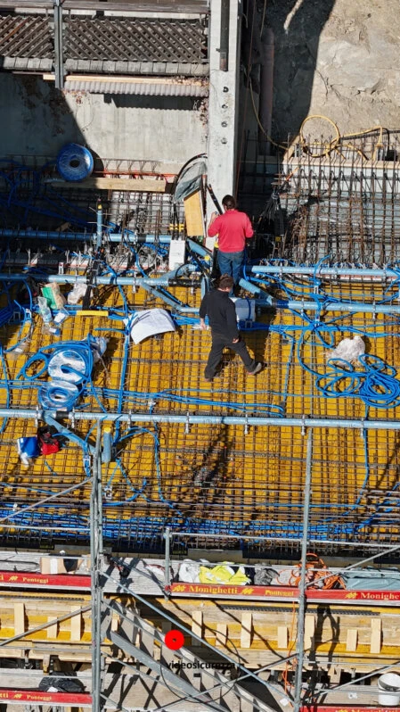 Operai al lavoro su armatura in ferro di un solaio in costruzione Vista aerea ravvicinata di due operai che lavorano su un solaio in cemento armato con armatura metallica e tubazioni elettriche in un cantiere edile